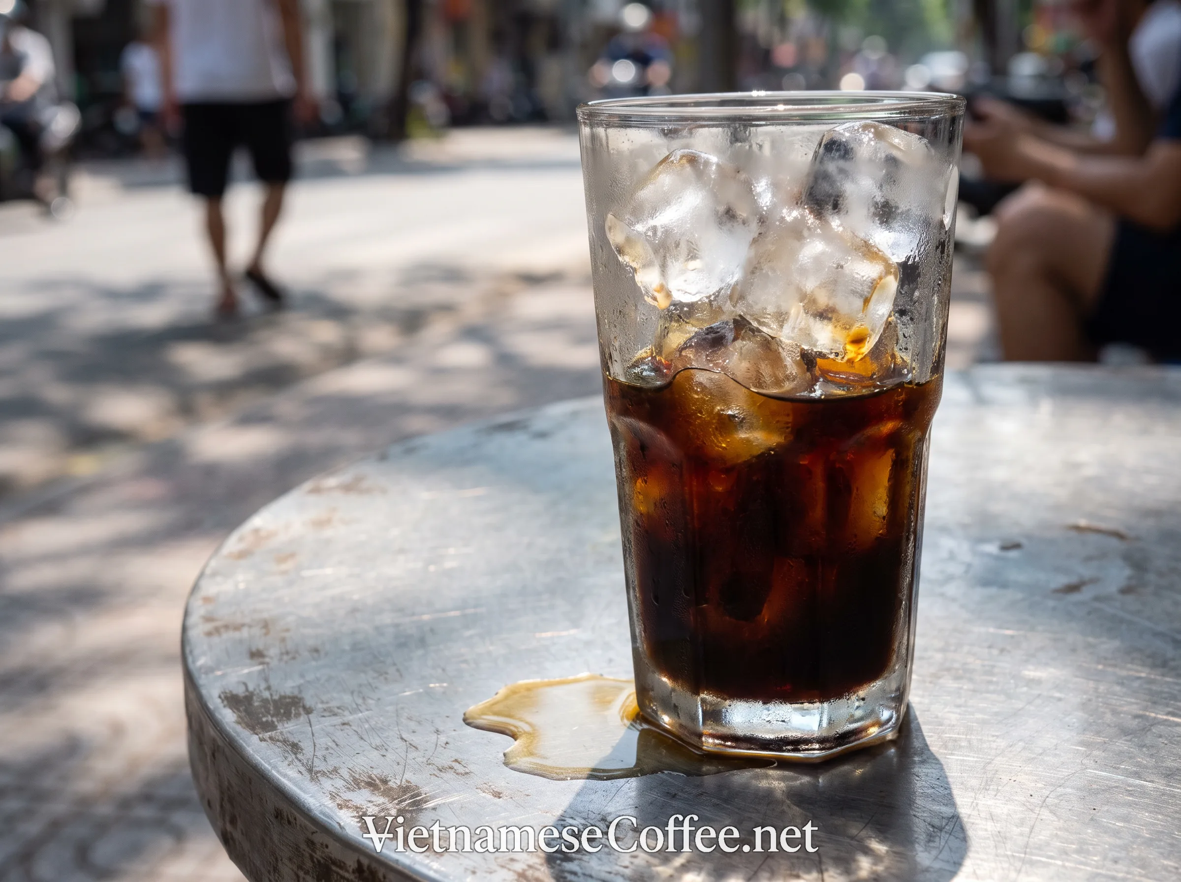 Tall glass of iced cà phê đen đá on a street-side table