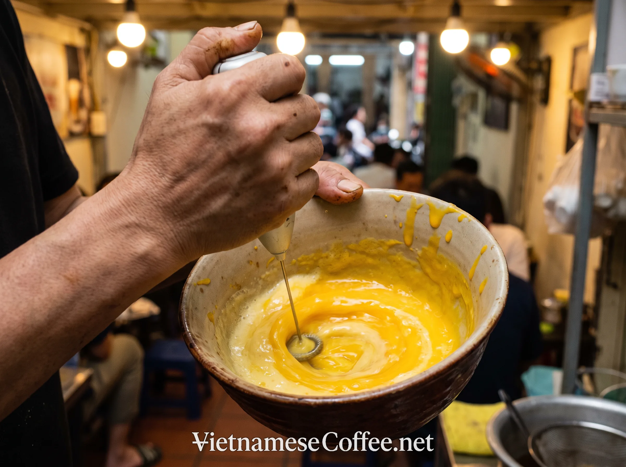 A barista whisking egg yolks and condensed milk for Cà phê trứng