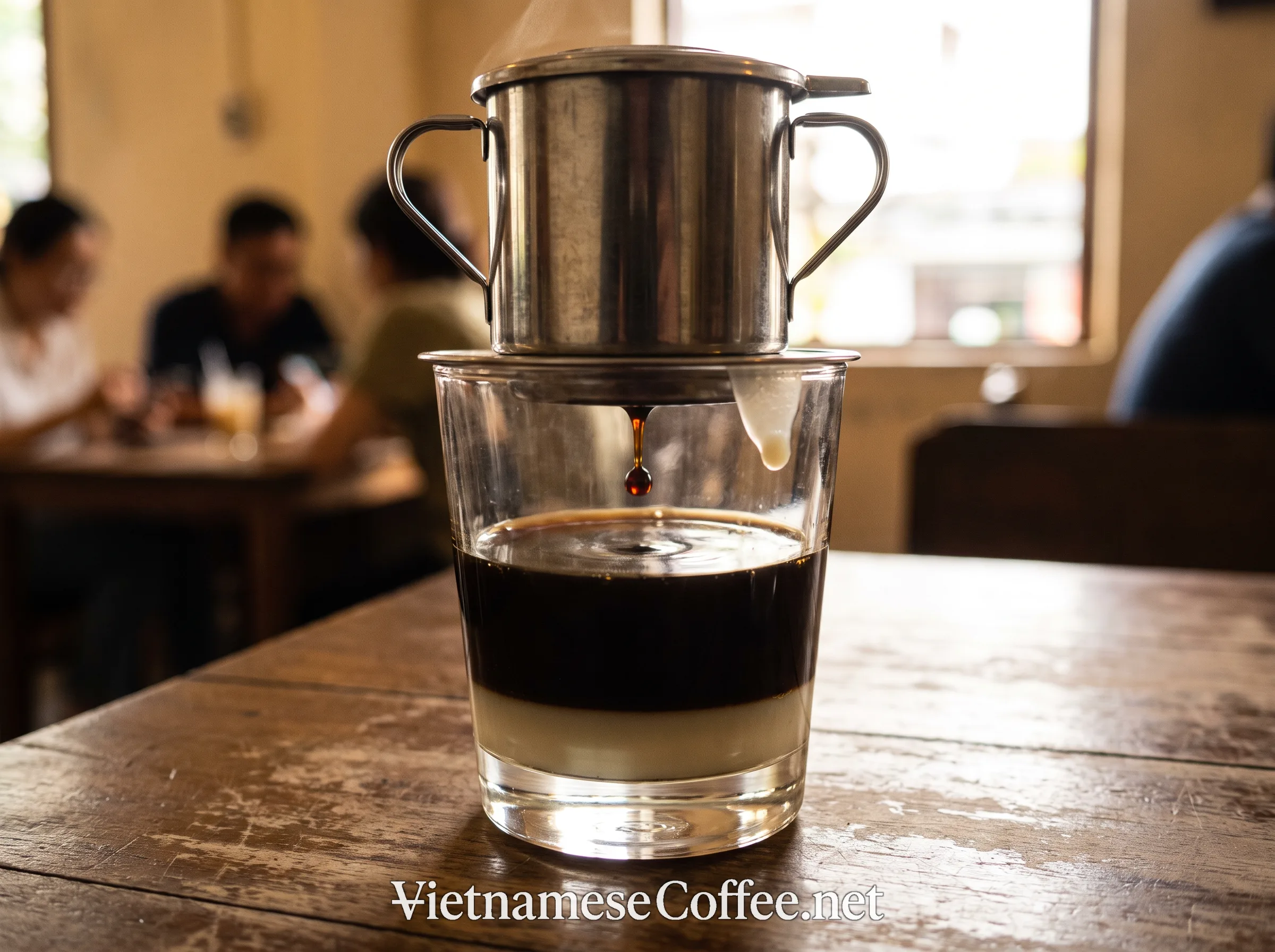 A traditional metal phin filter brewing thick culi robusta coffee over condensed milk